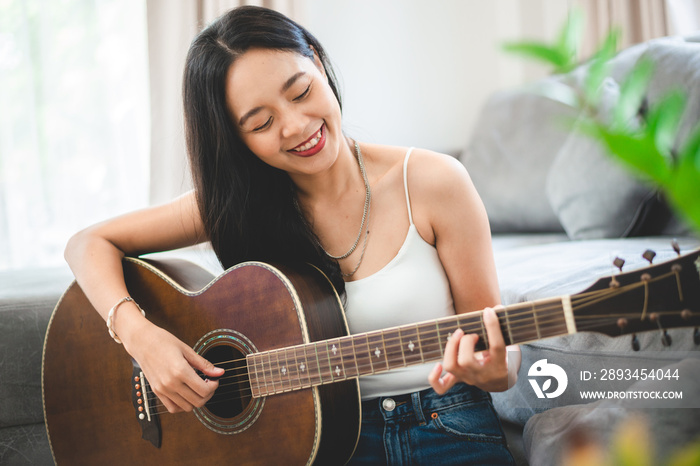 在家弹吉他的亚洲女性，年轻的女吉他手和原声音乐人的生活方式