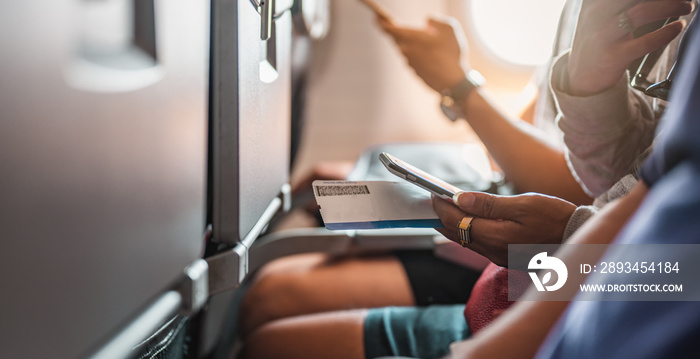 The tourists who are playing the phone and have a ticket on hand on the plane that is preparing to t