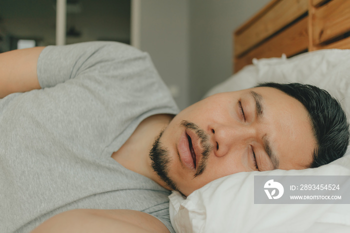 Close up man sleeping on his bed with snoring face. Concept of snoring.