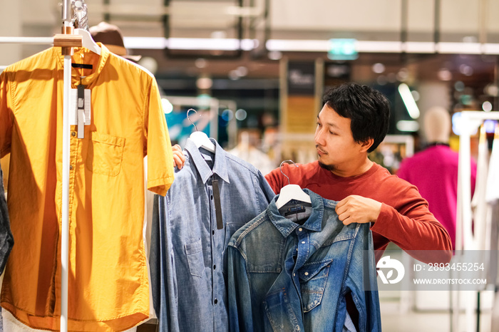 留胡子的聪明人在购物中心的服装店挑选衣服，比较差异