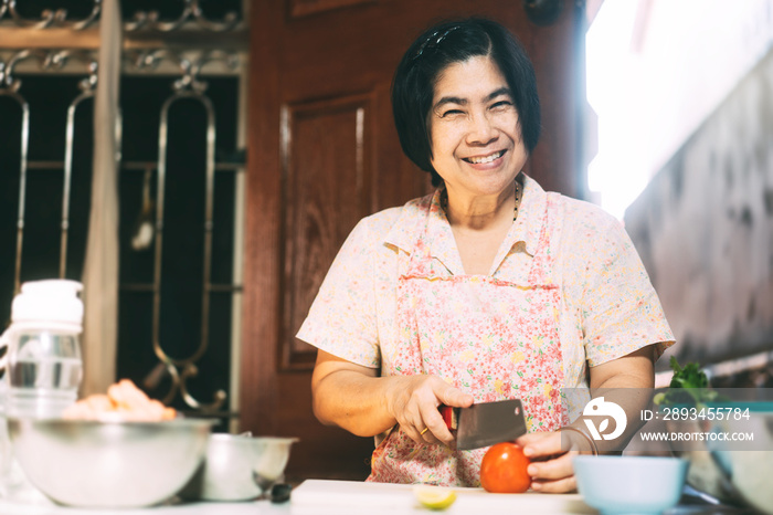 幸福的亚洲老年妇女在当地传统厨房为家人做饭的华丽画像