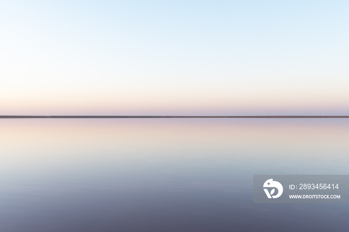 宁静的极简主义景观，粉色盐湖表面光滑，平静的水面和地平线