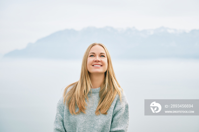 快乐美丽的年轻女子穿着灰色衣服在云端的山上放松的户外画像