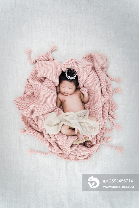 Portrait of newborn baby boy lying in a basket with silver crown.