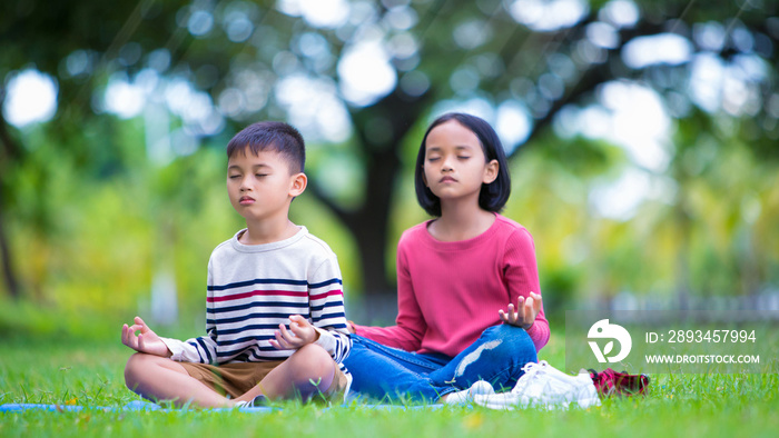 asian kids doing yoga pose in the park outdoor