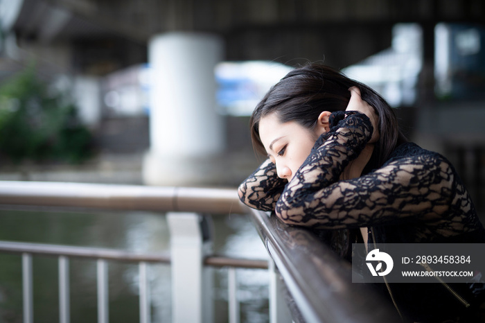 手すりにもたれて物思いにふける若く美しい日本人女性