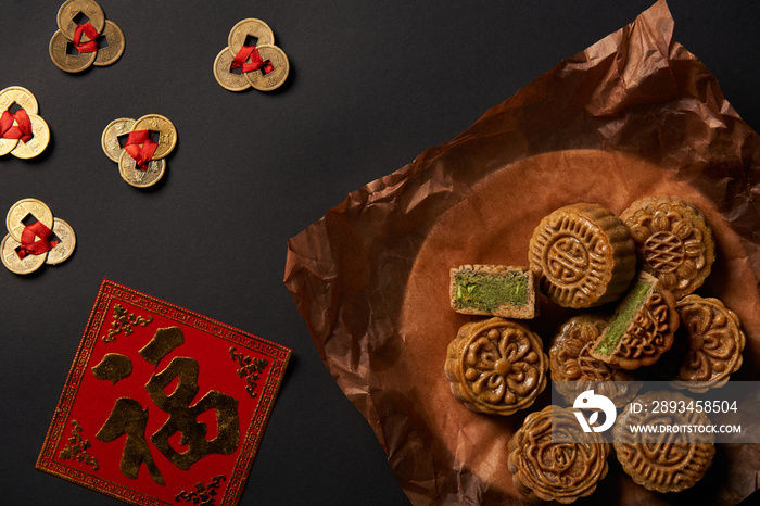 top view of traditional mooncakes with chinese talismans isolated on black