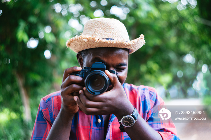 African man traveler on vacation photographing with a dslr camera on the green nature background