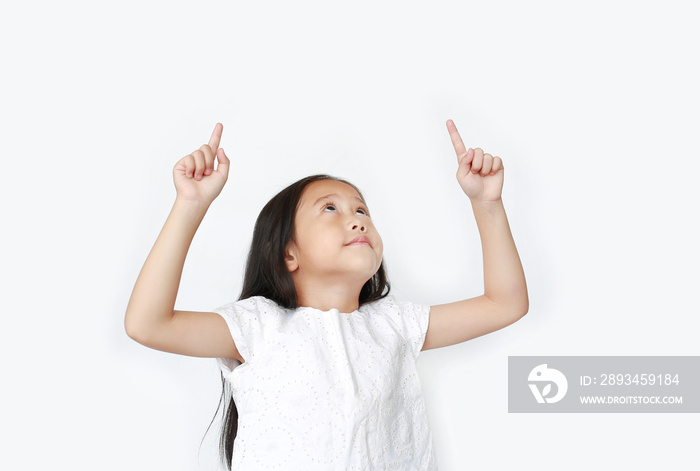 Portrait of Asian little child girl pointing two forefinger up and looking above isolated over white