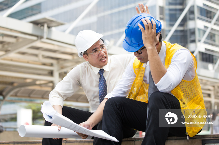 Engineers sitting in front of building with blueprint on hand,Businessman,Engineers reading in bluep