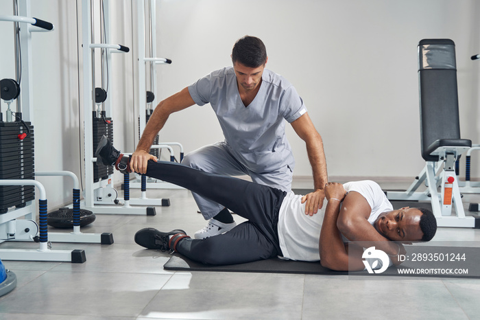 Physiatrist assessing lower body strength of man