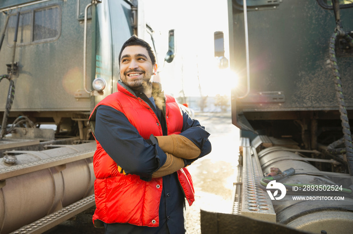 Confident worker standing by semi-trucks outdoors