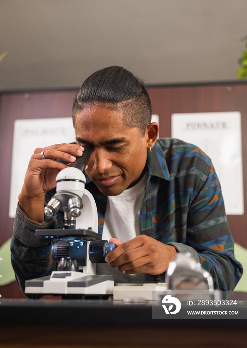 Vertical image of native man looking into a microscope