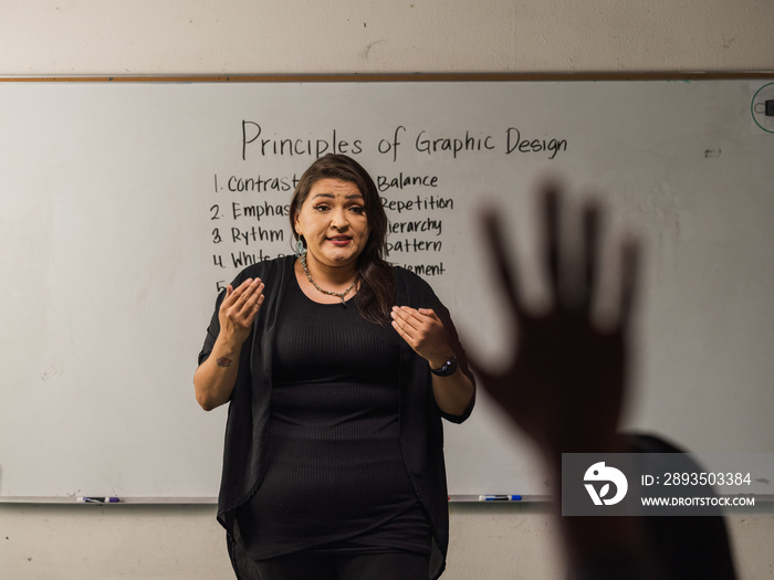 Teacher speaking while a student is raising their hand