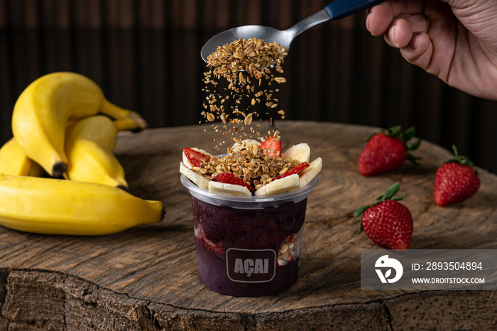 Delicious Brazilian Açaí Cream, in a plastic Cup With Strawberry, banana and granola Topping, in a r