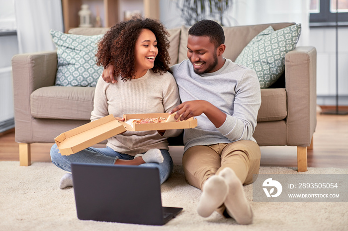 leisure, people and food concept - happy african american couple with laptop computer eating takeawa