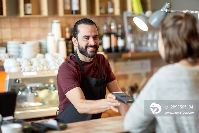 man or waiter with card reader and customer at bar