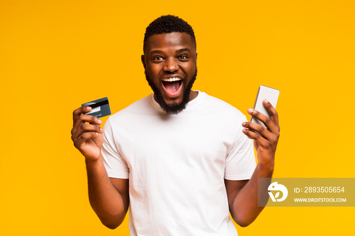 快乐的非洲男人，手里拿着信用卡和手机