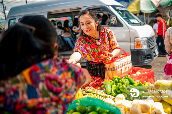 Dos mujeres indígenas en un puesto de verduras frescas.