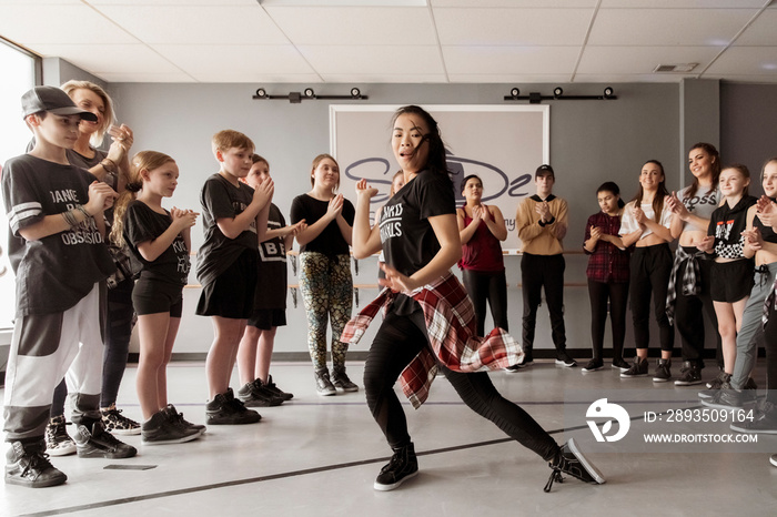 Dancers cheering young woman dancing in studio