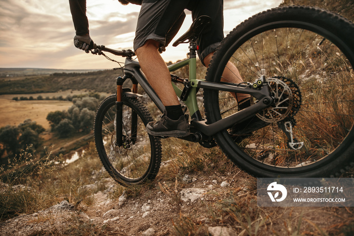 Crop man riding mountain bike