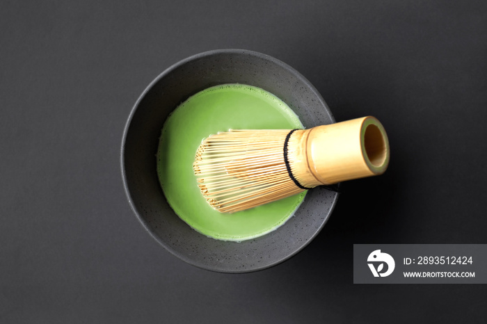 日本陶瓷茶杯中的有机抹茶绿茶，黑底竹茶搅拌器