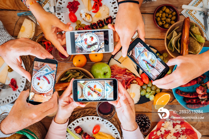 Top view of group of people during christmas night taking food and dishes picture with smartphone al