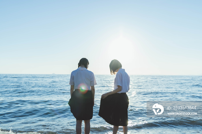 夕暮れの海にいる女子高生