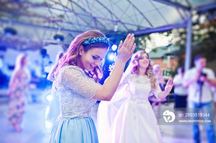 Bridesmaid with bride dancing on wedding party.