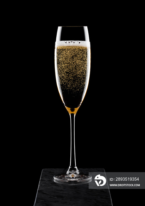 一杯优雅的黄色香槟，黑色背景的黑色大理石板上有气泡。