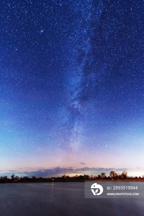 河岸上一个神奇的星空之夜，天空中有乳白色的银河，冬天有落下的星星