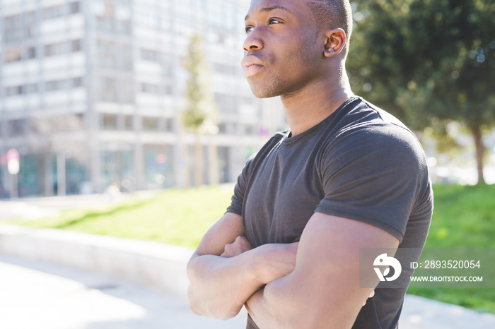 Portrait of young man outdoors, arms folded, pensive expression