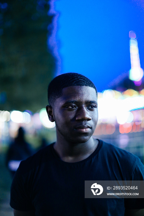 Portrait of teenage boy at funfair at night