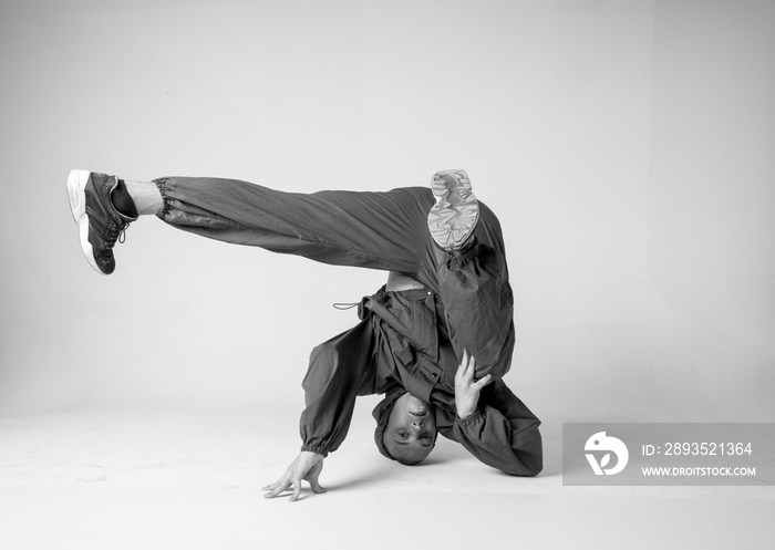 A man hip hop dancer or bboy freezes in one pose on a white background. Bboy doing stylish stunts.