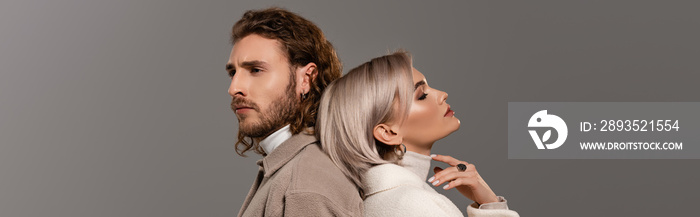 panoramic shot of woman in white coat with closed eyes and man in shirt isolated on grey