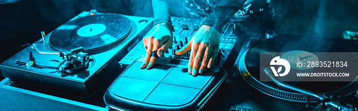 panoramic shot of dj girl using dj equipment in nightclub with smoke