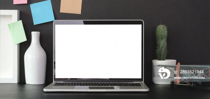 Cropped shot of trendy office room with mock-up laptop computer and office supplies on black table w