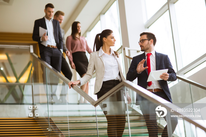 Business partners analyze the business results while walking down the stairs in modern office