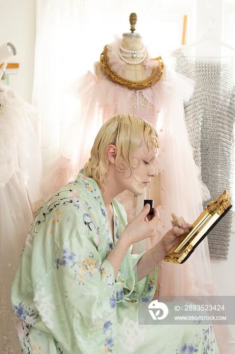 non-binary hispanic person with blonde hair putting makeup on