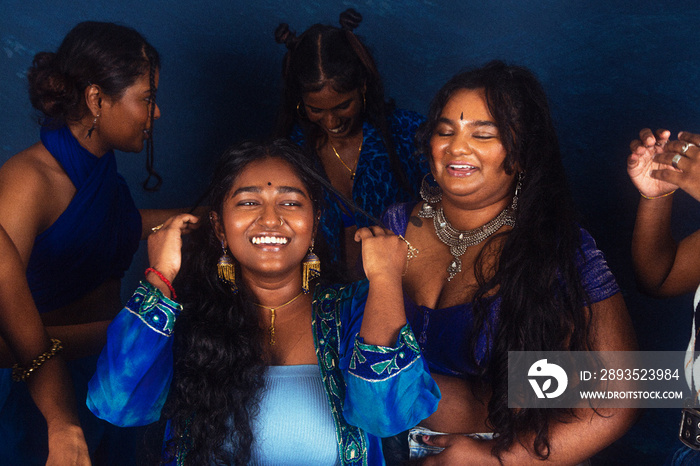 group portraits of dark skinned Indian women from Malaysia against a dark blue background, laughing