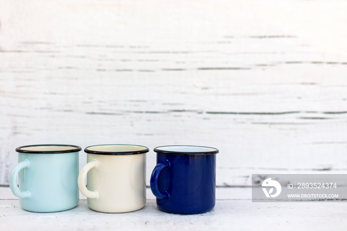 Enameled mugs in retro style on an old wooden background.