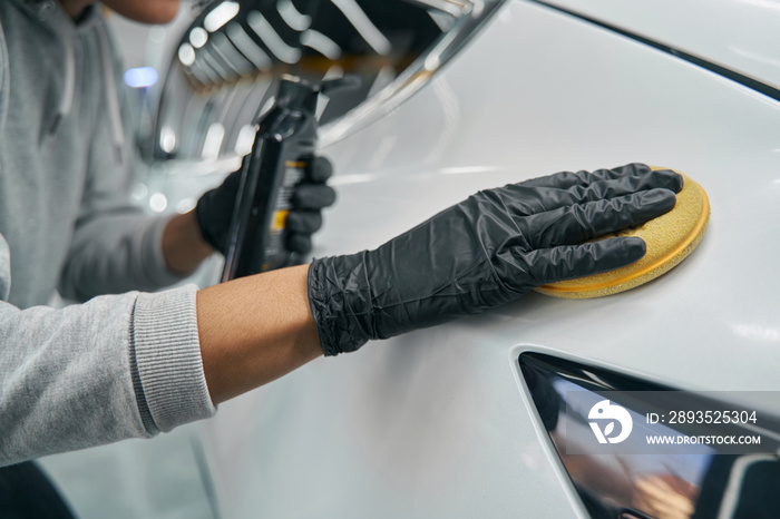 Detailer using liquid wax and foam pad for car buffing