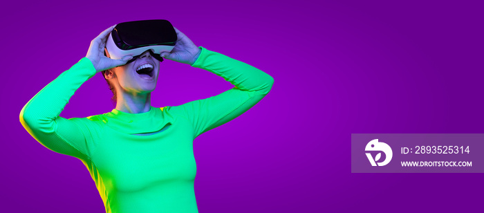 身穿绿色上衣的兴奋女孩的横幅，戴着虚拟现实耳机，被VR游戏惊艳，iso