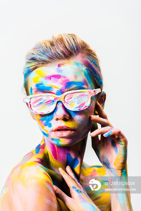 attractive girl with colorful bright body art and sunglasses touching herself isolated on white