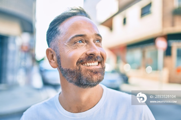 Middle age handsome man smiling happy looking to the side at the city.