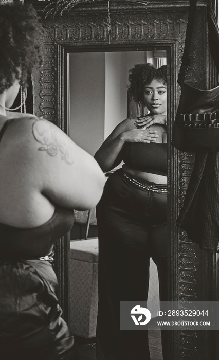 Black woman looking in mirror admiring herself