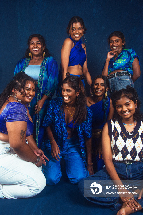 group portraits of dark skinned Indian women from Malaysia against a dark blue background, laughing