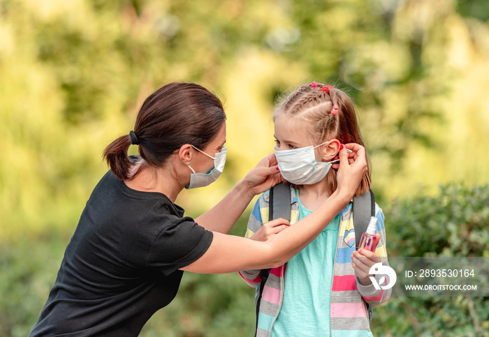 Mother putting mask on daughter before school