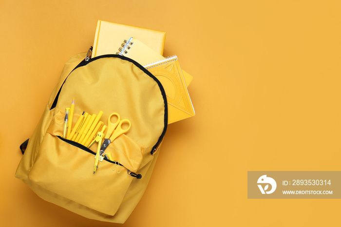 School backpack with stationery on color background