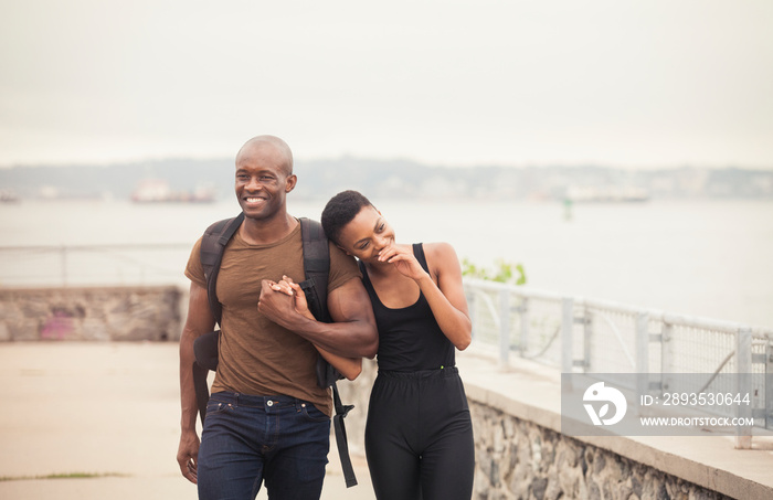 Smiling couple holding hands while walking on footpath